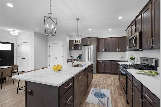 306 NW 3rd St, Monroe, WI 53566 - kitchen with pendant lighting, dark brown cabinets, a sink, appliances with stainless steel finishes, and a notable chandelier