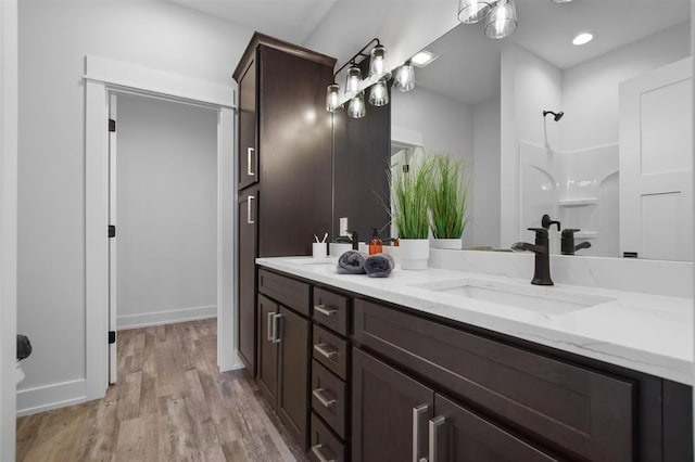 306 NW 3rd St, Monroe, WI 53566 - full bathroom with double vanity, a sink, walk in shower, and wood finished floors