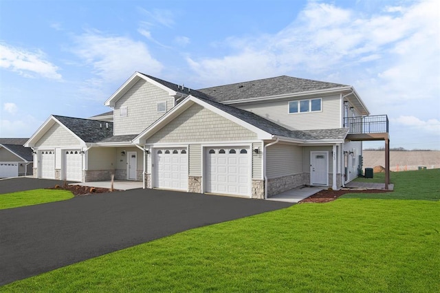 223 NW 3rd Ave, Monroe, WI 53566 - view of front facade with aphalt driveway, a balcony, a front lawn, an attached garage, and stone siding