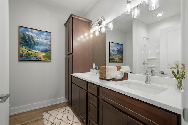 223 NW 3rd Ave, Monroe, WI 53566 - bathroom featuring double vanity, a shower, wood finished floors, a sink, and baseboards