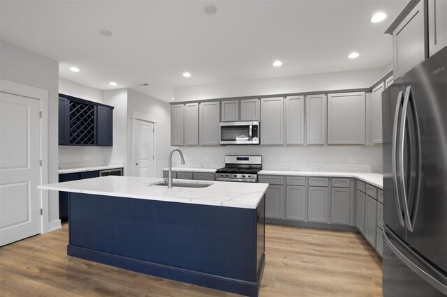 223 NW 3rd Ave, Monroe, WI 53566 - kitchen featuring light stone countertops, a sink, light wood finished floors, appliances with stainless steel finishes, and gray cabinetry