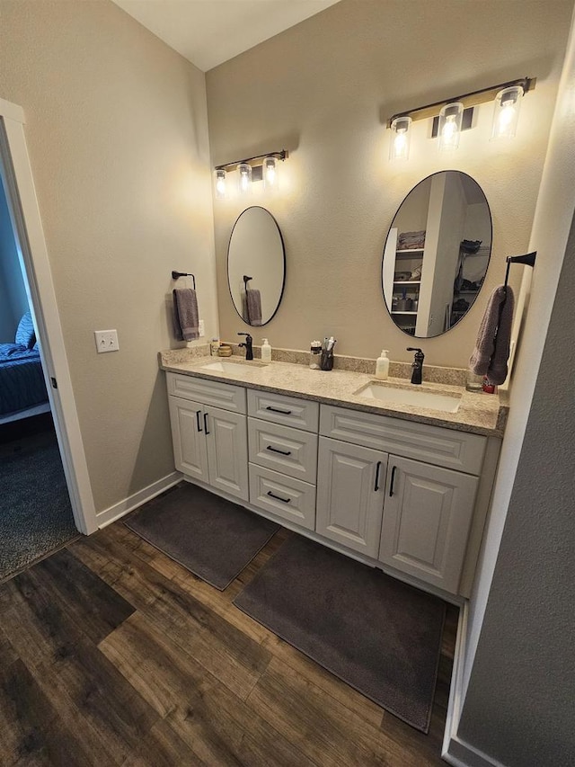 456 N Hyland St, Juneau, WI 53039 - bathroom featuring wood finished floors, double vanity, ensuite bathroom, and baseboards