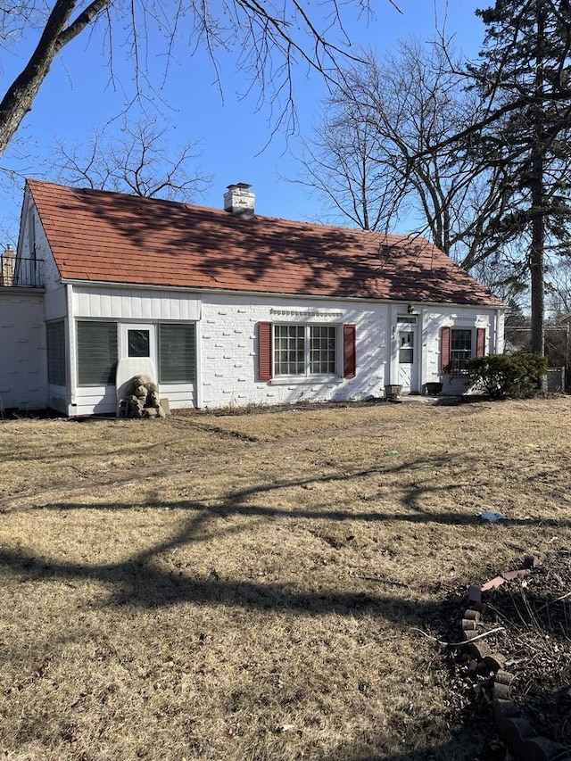back of property featuring a lawn and a chimney