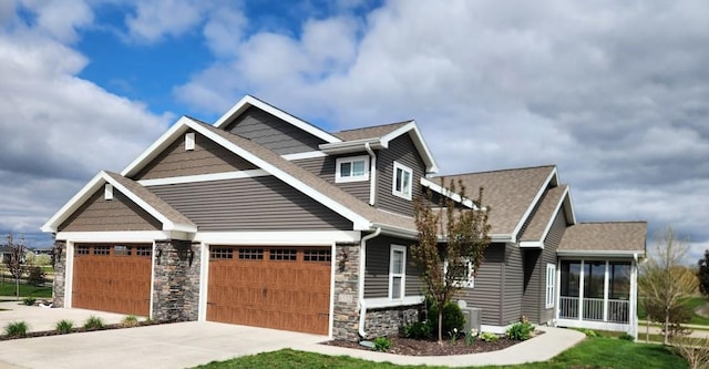 craftsman-style house featuring roof with shingles, an attached garage, driveway, and stone siding