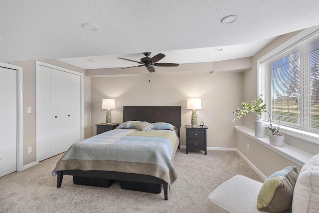 carpeted bedroom featuring baseboards, a ceiling fan, and a textured ceiling