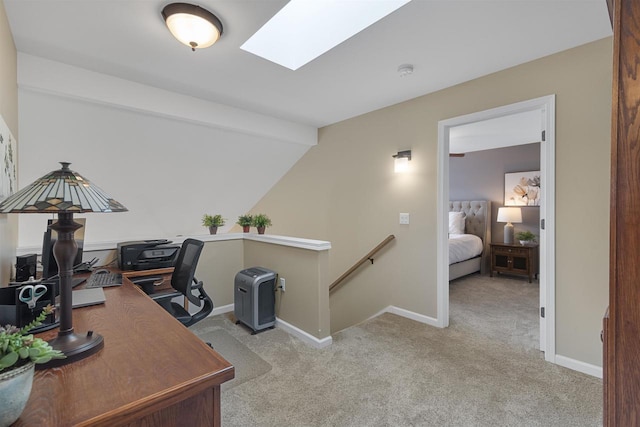 office area with baseboards, lofted ceiling with skylight, and carpet