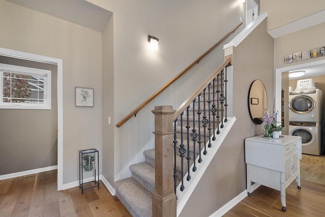 stairway featuring stacked washer and clothes dryer, baseboards, and hardwood / wood-style floors