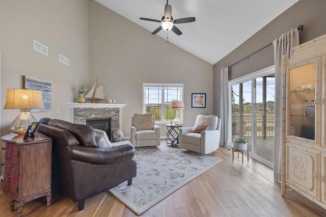living room with a ceiling fan, a fireplace, visible vents, and high vaulted ceiling