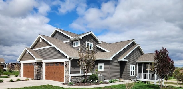craftsman-style house featuring roof with shingles, an attached garage, stone siding, a sunroom, and concrete driveway