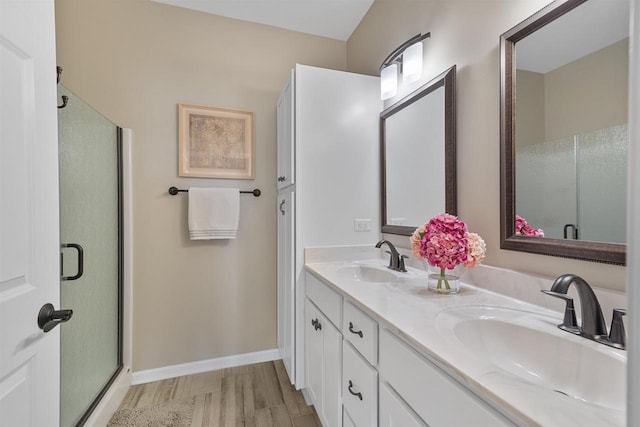 full bathroom featuring double vanity, baseboards, a shower stall, and a sink
