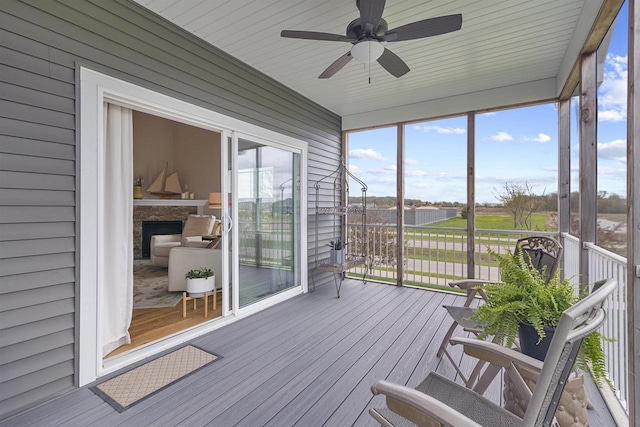 sunroom / solarium featuring a ceiling fan and a fireplace