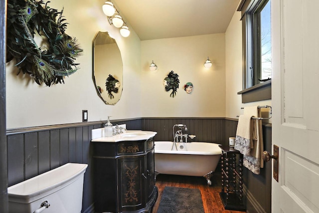 N1453 Clover Rd, Genoa City, WI 53128 - bathroom featuring wainscoting, vanity, toilet, a freestanding tub, and wood finished floors