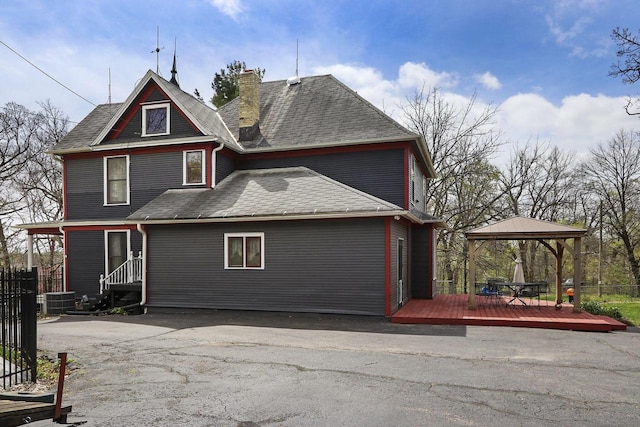 N1453 Clover Rd, Genoa City, WI 53128 - back of house with a shingled roof, a gazebo, a wooden deck, central AC unit, and a chimney
