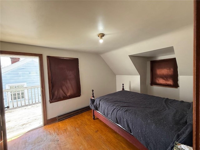 bedroom with access to outside, vaulted ceiling, a baseboard heating unit, and light wood-type flooring
