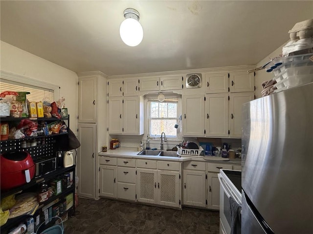 kitchen with a sink, white range with electric stovetop, freestanding refrigerator, and light countertops