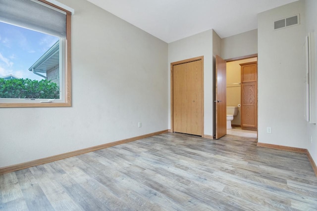 524 Tindalls Nest, Twin Lakes, WI 53181 - unfurnished bedroom featuring connected bathroom, baseboards, visible vents, and wood finished floors