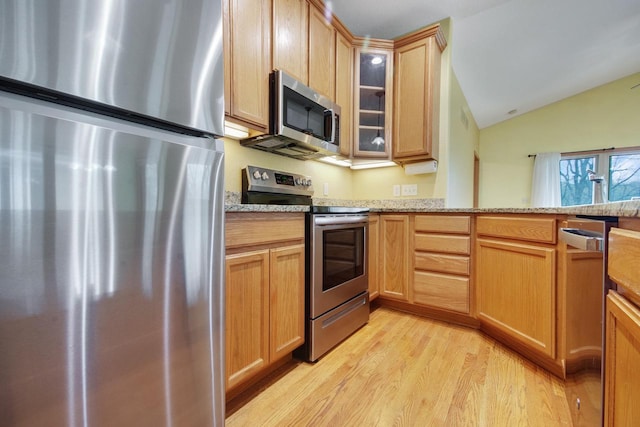 524 Tindalls Nest, Twin Lakes, WI 53181 - kitchen with lofted ceiling, light stone countertops, glass insert cabinets, light wood-style floors, and stainless steel appliances