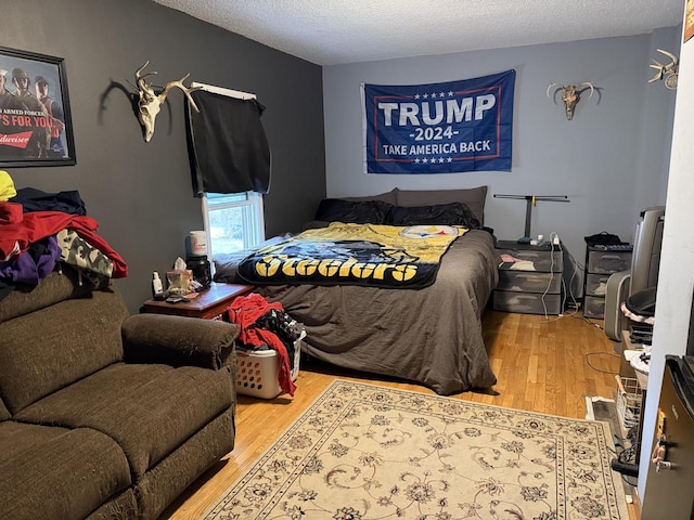 bedroom with a textured ceiling and wood finished floors