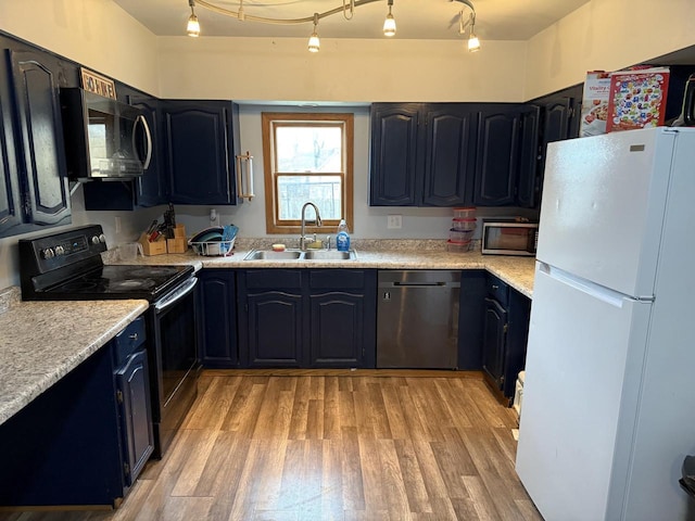 kitchen featuring a sink, track lighting, light wood-style floors, and stainless steel appliances