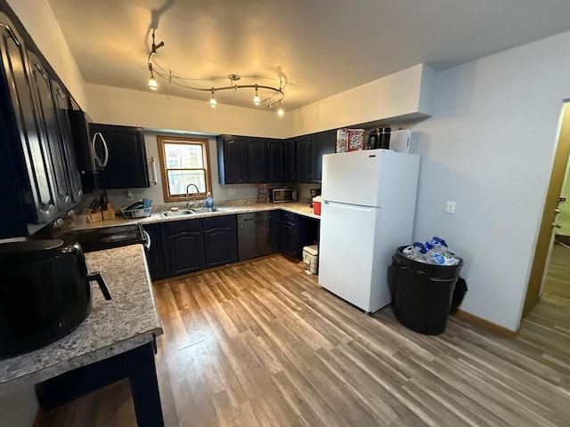 kitchen with a sink, light wood finished floors, light countertops, baseboards, and black appliances