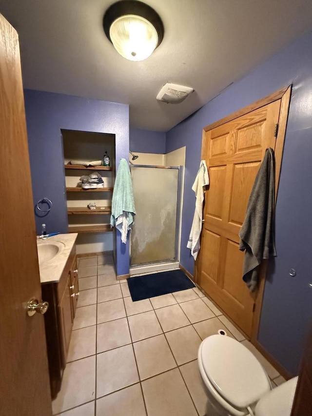 bathroom featuring tile patterned flooring, a stall shower, toilet, and vanity
