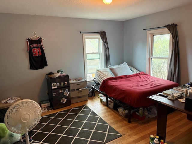 bedroom with multiple windows and wood finished floors