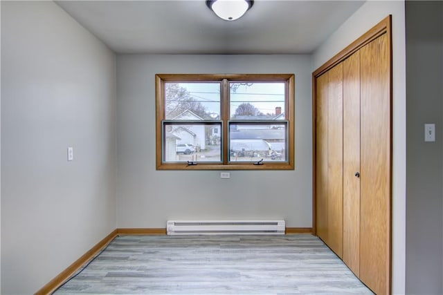 208 W Grand Ave, Chippewa Falls, WI 54729 - unfurnished bedroom with baseboards, baseboard heating, light wood finished floors, and a closet