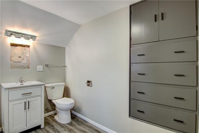 208 W Grand Ave, Chippewa Falls, WI 54729 - half bath featuring vanity, wood finished floors, toilet, baseboards, and vaulted ceiling