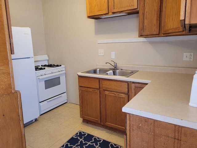 kitchen with white appliances, light countertops, brown cabinets, a sink, and light tile patterned floors