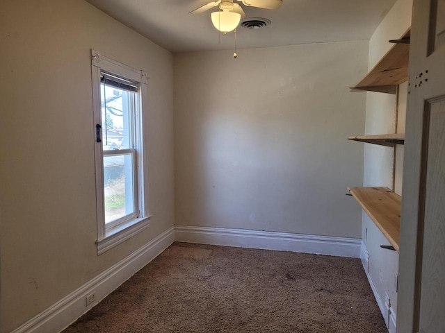 spare room featuring ceiling fan, visible vents, a wealth of natural light, and carpet