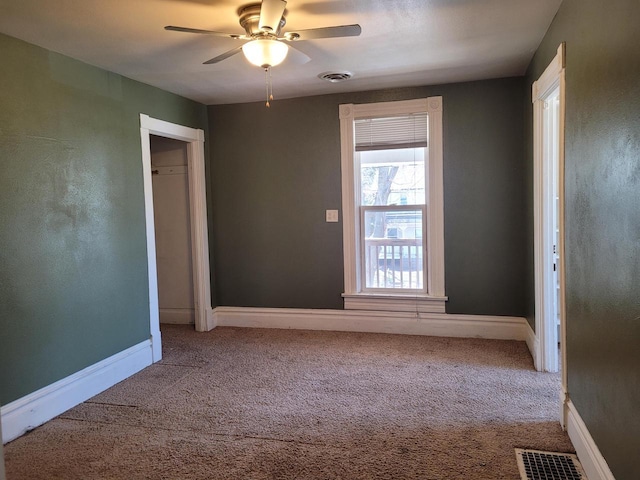 unfurnished room with carpet flooring, baseboards, visible vents, and ceiling fan
