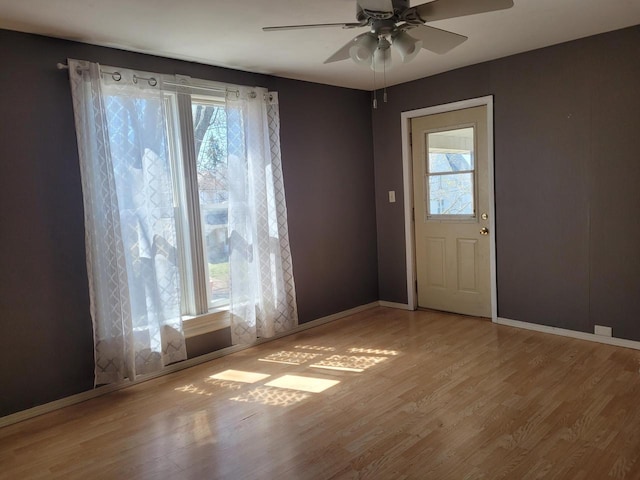 interior space with ceiling fan, baseboards, plenty of natural light, and wood finished floors