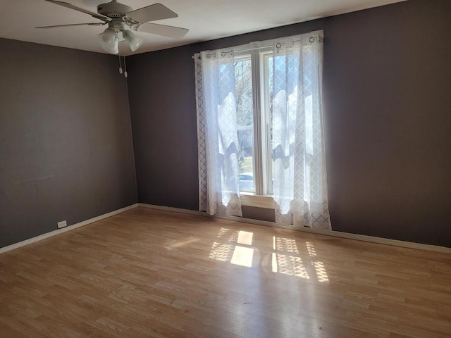 empty room featuring baseboards, a ceiling fan, and wood finished floors