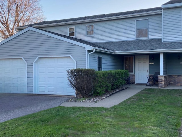 multi unit property with a garage, aphalt driveway, a front yard, and a shingled roof