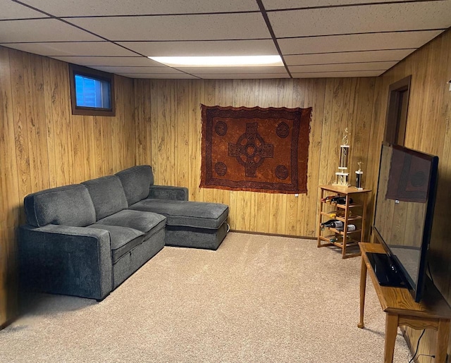 living area with wooden walls, a drop ceiling, and carpet