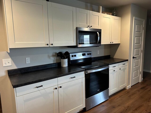 1817 Ridgewood Cir, Menomonie, WI 54751 - kitchen featuring stainless steel appliances, dark wood finished floors, dark countertops, and white cabinets