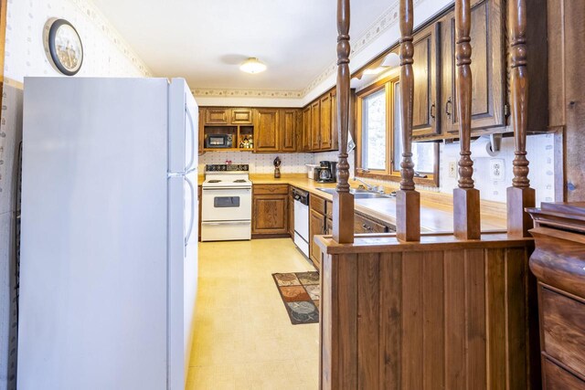 101224 25th St, Chetek, WI 54728 - kitchen with brown cabinetry, white appliances, light floors, wallpapered walls, and a sink
