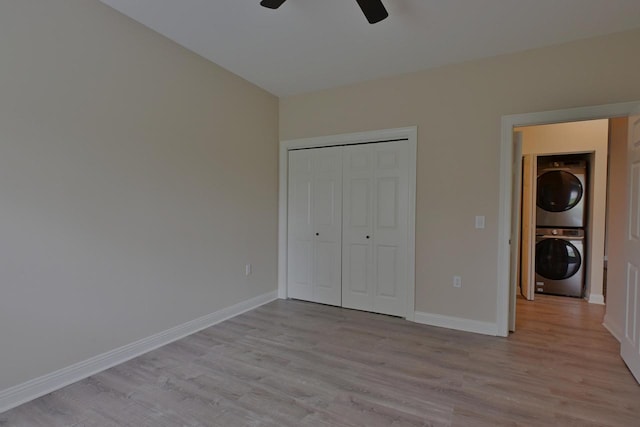unfurnished bedroom with baseboards, light wood-type flooring, a closet, and stacked washer and dryer