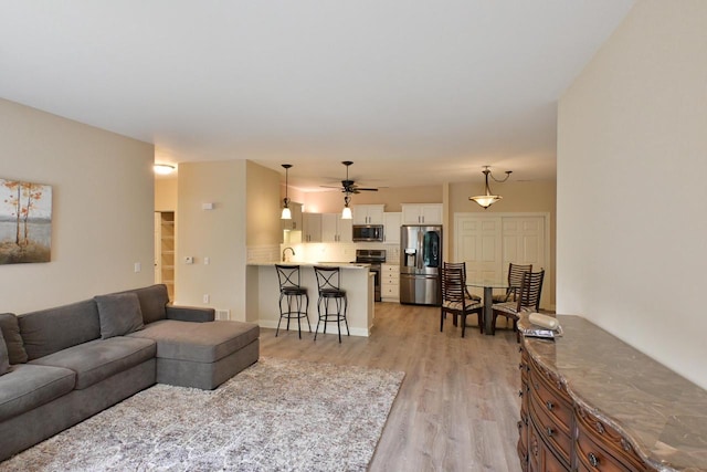 living room with a ceiling fan and light wood-style flooring