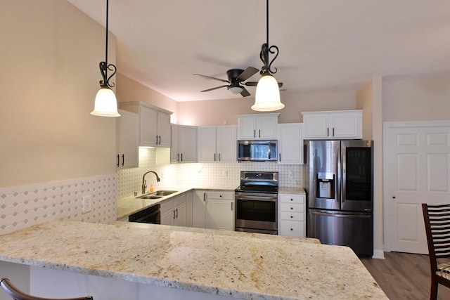 kitchen featuring ceiling fan, a sink, stainless steel appliances, white cabinetry, and a peninsula