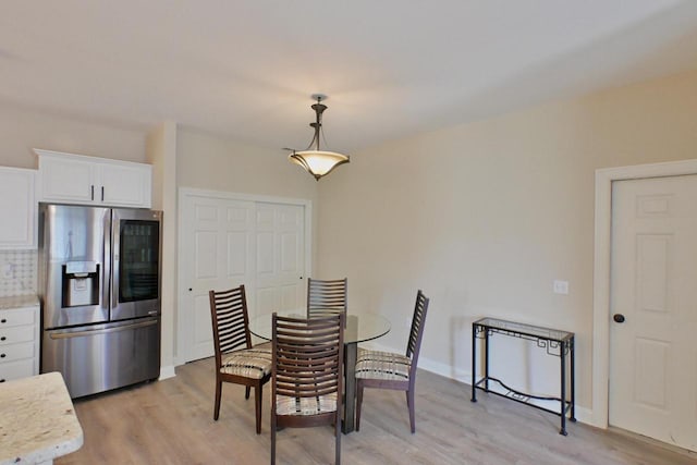 dining space featuring baseboards and light wood-style flooring
