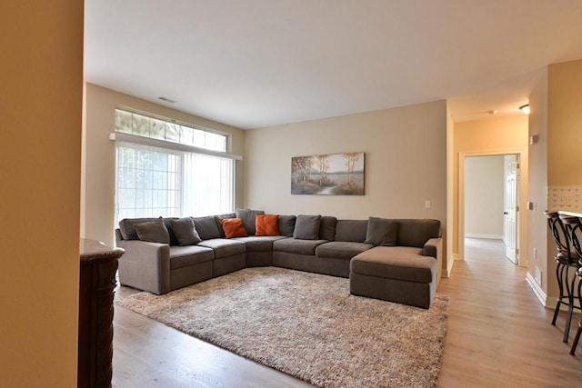 living room with visible vents, light wood-style flooring, and baseboards
