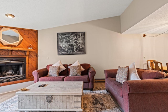 living area featuring a baseboard heating unit, wood finished floors, vaulted ceiling, and a large fireplace