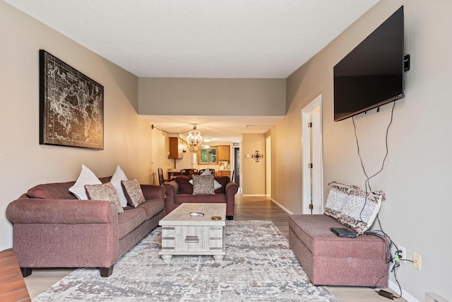 living room featuring baseboards, wood finished floors, and a notable chandelier