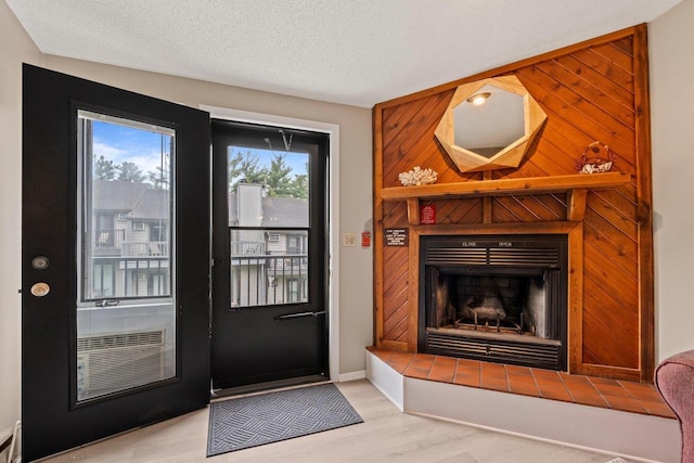 entryway with a tiled fireplace, a textured ceiling, and wood finished floors