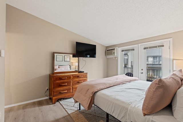 bedroom with french doors, an AC wall unit, lofted ceiling, light wood-style floors, and access to outside