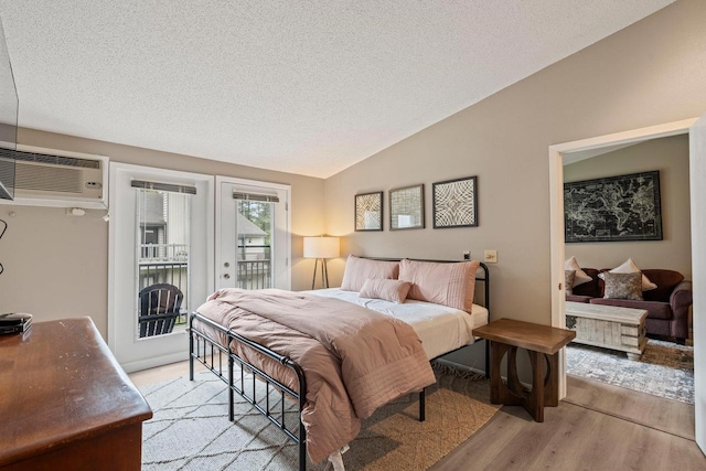 bedroom with access to outside, a textured ceiling, lofted ceiling, and light wood-type flooring