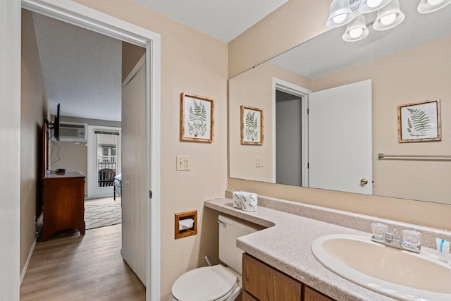half bathroom featuring vanity, baseboards, wood finished floors, and toilet