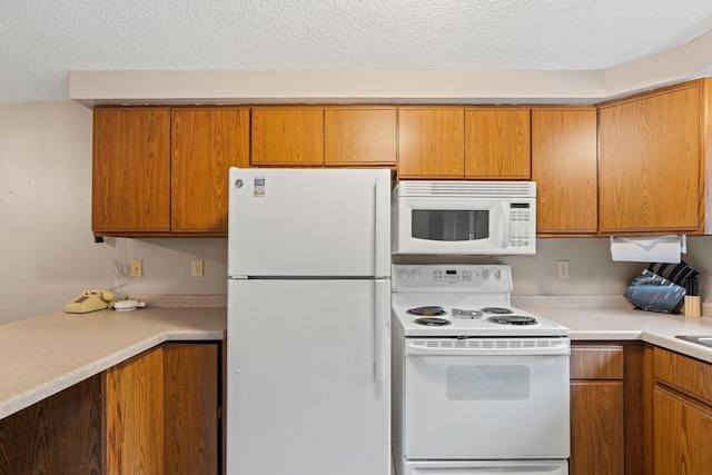kitchen with brown cabinetry, light countertops, a textured ceiling, and white appliances