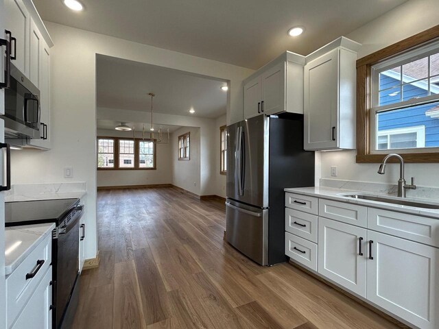 1019 Ellis Ave, Ashland, WI 54806 - kitchen with dark wood-style floors, white cabinetry, light stone counters, a sink, and stainless steel appliances